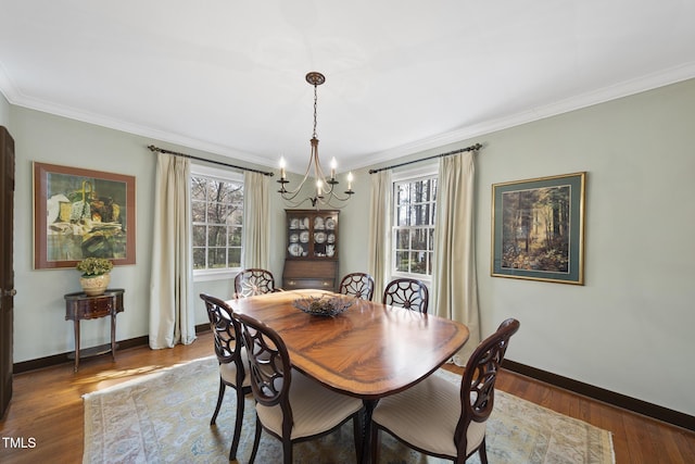 dining area with dark wood-type flooring, ornamental molding, and a notable chandelier