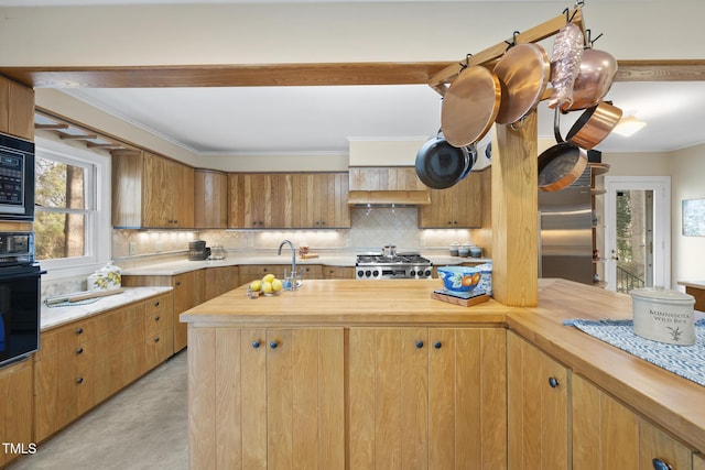 kitchen with butcher block counters, backsplash, built in appliances, ornamental molding, and custom exhaust hood