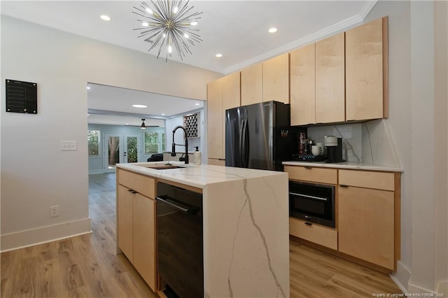 kitchen with an inviting chandelier, refrigerator, a kitchen island with sink, and light brown cabinets