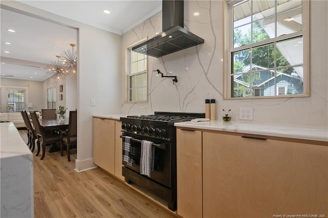 kitchen with light hardwood / wood-style flooring, black gas range oven, island exhaust hood, light stone countertops, and backsplash