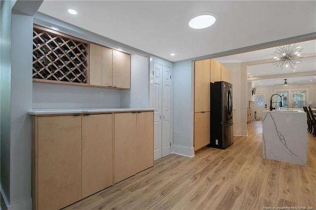 kitchen with black refrigerator, light brown cabinetry, and light hardwood / wood-style floors