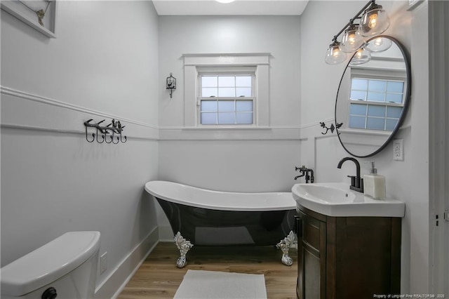 bathroom with wood-type flooring, a tub to relax in, vanity, and toilet