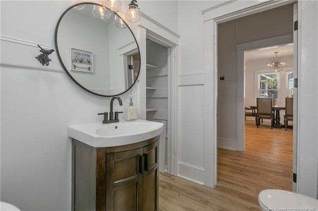 bathroom featuring hardwood / wood-style flooring, vanity, toilet, and a chandelier