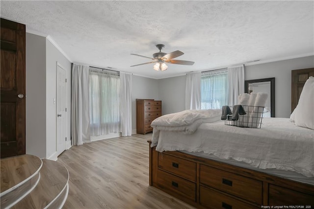 bedroom with ceiling fan, crown molding, light hardwood / wood-style flooring, and a textured ceiling