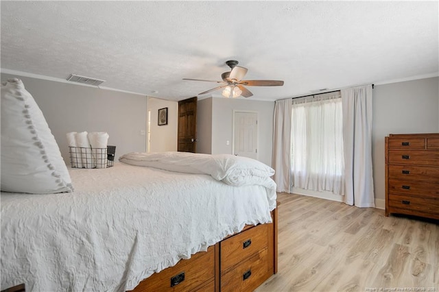 bedroom with ceiling fan, ornamental molding, a textured ceiling, and light hardwood / wood-style floors