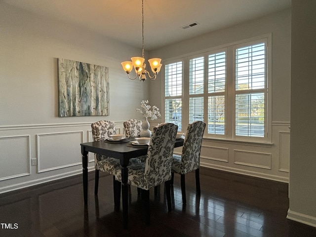 dining room with dark wood-type flooring and an inviting chandelier