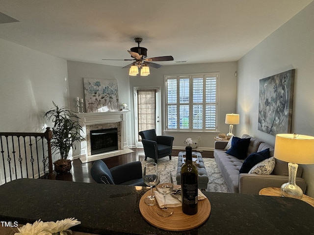 living room featuring hardwood / wood-style flooring, ceiling fan, and a fireplace