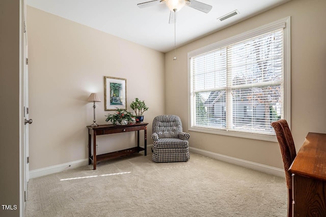 living area featuring light carpet and ceiling fan