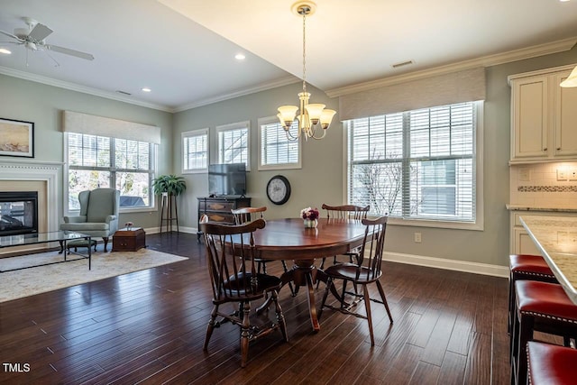 dining space with dark wood-type flooring, ornamental molding, and ceiling fan with notable chandelier