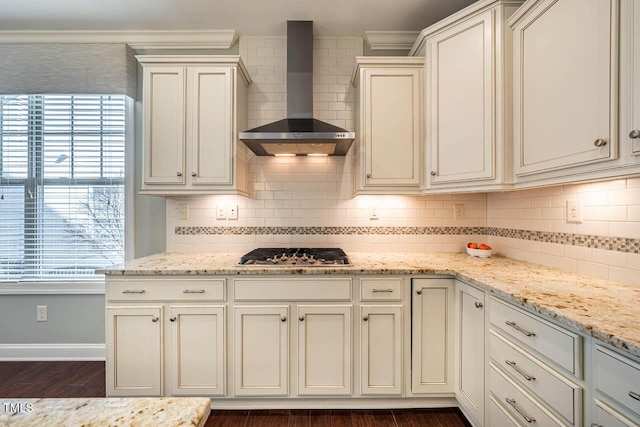 kitchen with light stone counters, wall chimney exhaust hood, stainless steel gas cooktop, and backsplash