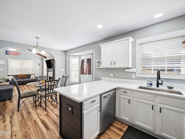 kitchen with sink, light hardwood / wood-style flooring, white cabinetry, stainless steel dishwasher, and kitchen peninsula