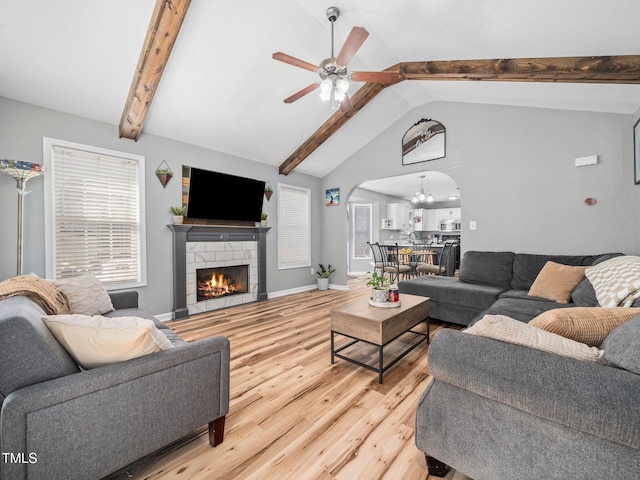 living room with ceiling fan with notable chandelier, lofted ceiling with beams, and light hardwood / wood-style flooring