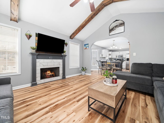 living room featuring light hardwood / wood-style flooring, a fireplace, lofted ceiling with beams, and ceiling fan