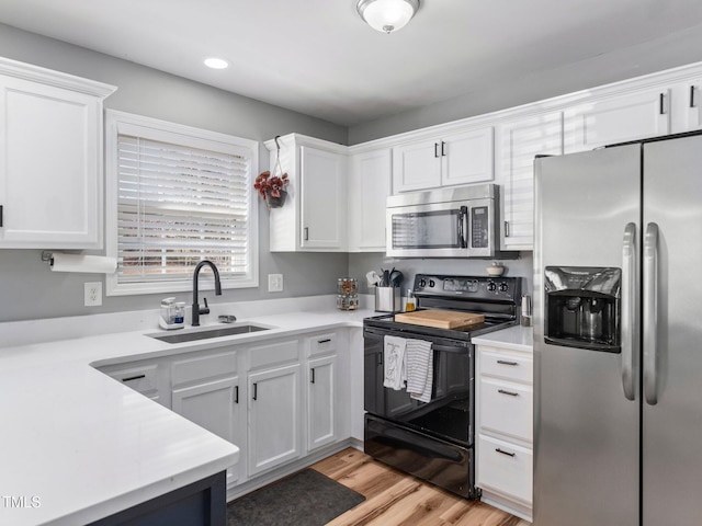 kitchen with white cabinetry, appliances with stainless steel finishes, sink, and light wood-type flooring