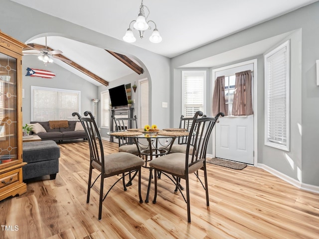 dining room with ceiling fan with notable chandelier, light hardwood / wood-style flooring, and lofted ceiling with beams