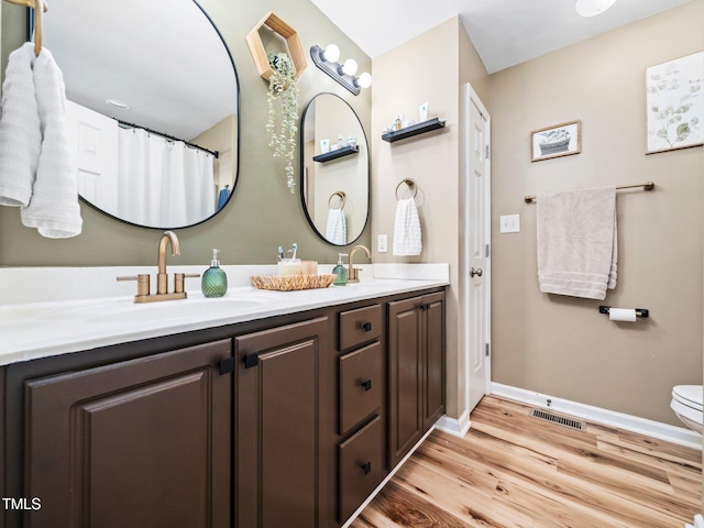 bathroom featuring wood-type flooring, toilet, and vanity