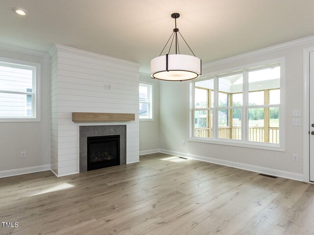 1813 Bright Lantern Way, Wendell, NC 27591 - unfurnished living room featuring ornamental molding, baseboards, wood finished floors, plenty of natural light, and a fireplace