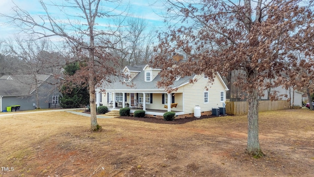 cape cod-style house with covered porch, a front yard, and central air condition unit