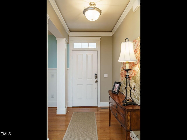 foyer featuring crown molding, hardwood / wood-style floors, and ornate columns