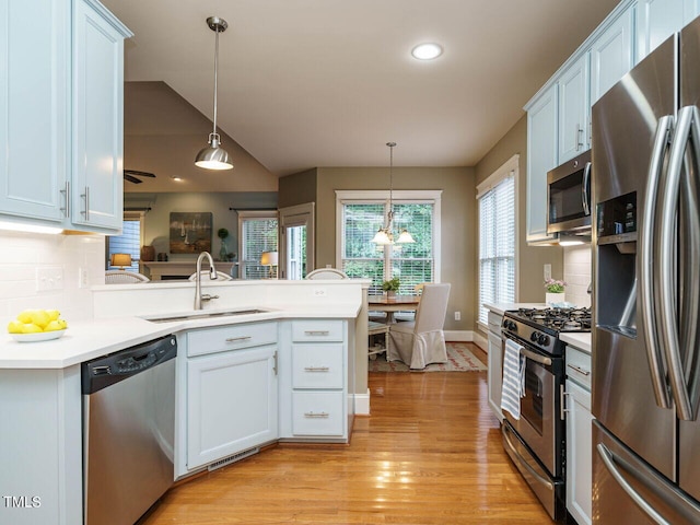 kitchen featuring sink, stainless steel appliances, hanging light fixtures, and white cabinets