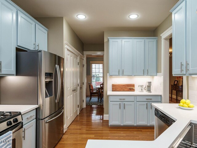 kitchen with white cabinetry, decorative backsplash, light hardwood / wood-style flooring, and stainless steel appliances