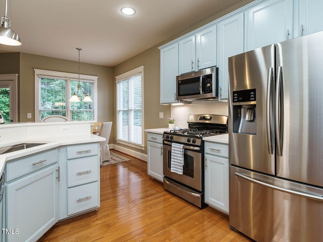 kitchen featuring appliances with stainless steel finishes, sink, pendant lighting, and white cabinets