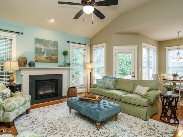 living room with hardwood / wood-style flooring, ceiling fan with notable chandelier, and vaulted ceiling