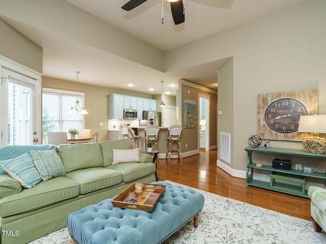 living room with hardwood / wood-style flooring and ceiling fan with notable chandelier