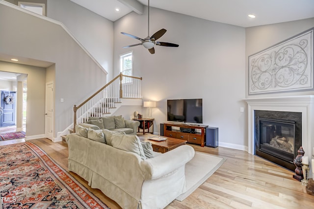 living room with ceiling fan, beam ceiling, high vaulted ceiling, and light hardwood / wood-style flooring