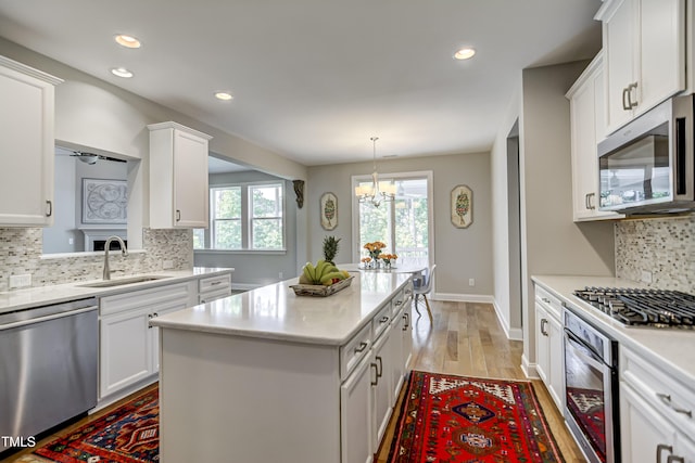 kitchen featuring stainless steel appliances, white cabinetry, a kitchen island, and sink