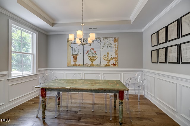 dining area featuring dark wood-type flooring, crown molding, a raised ceiling, and an inviting chandelier