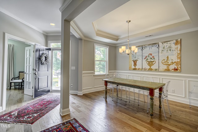 dining space featuring hardwood / wood-style flooring, ornamental molding, a chandelier, and a tray ceiling