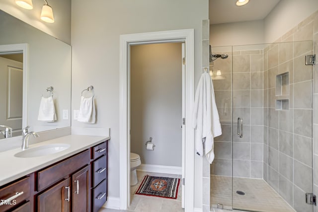 bathroom with vanity, a shower with door, and toilet