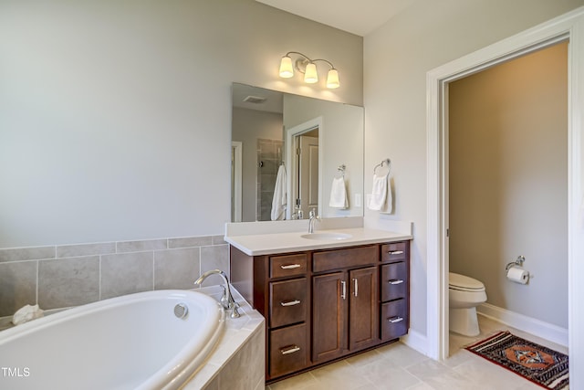 bathroom featuring tiled tub, vanity, tile patterned flooring, and toilet