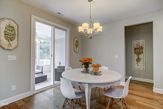 dining area featuring hardwood / wood-style flooring and an inviting chandelier