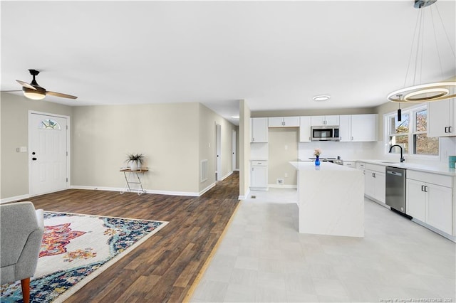 kitchen with sink, white cabinetry, decorative light fixtures, a kitchen island, and stainless steel appliances