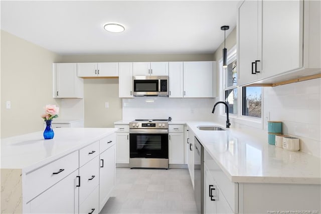 kitchen featuring decorative light fixtures, white cabinetry, sink, decorative backsplash, and stainless steel appliances