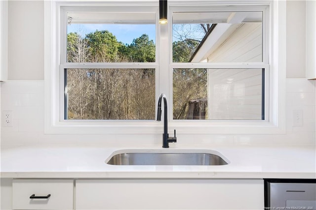 kitchen featuring pendant lighting, sink, decorative backsplash, and white cabinets