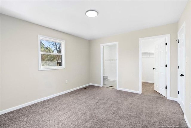 unfurnished bedroom with a walk in closet, carpet floors, connected bathroom, and a closet