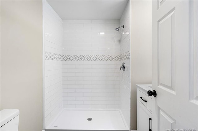 bathroom with a tile shower and toilet