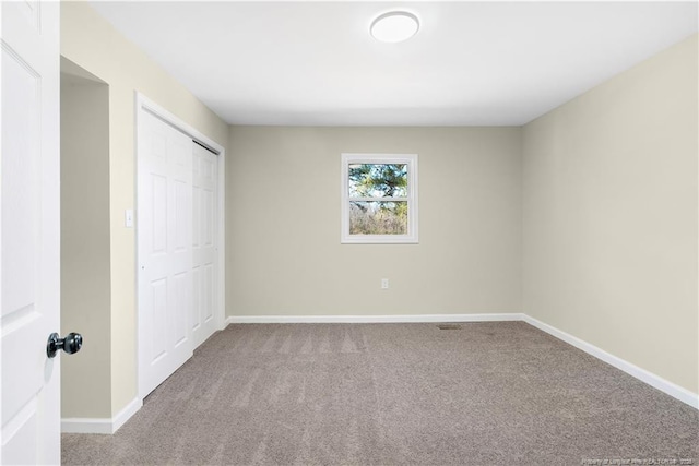 unfurnished bedroom featuring light colored carpet and a closet