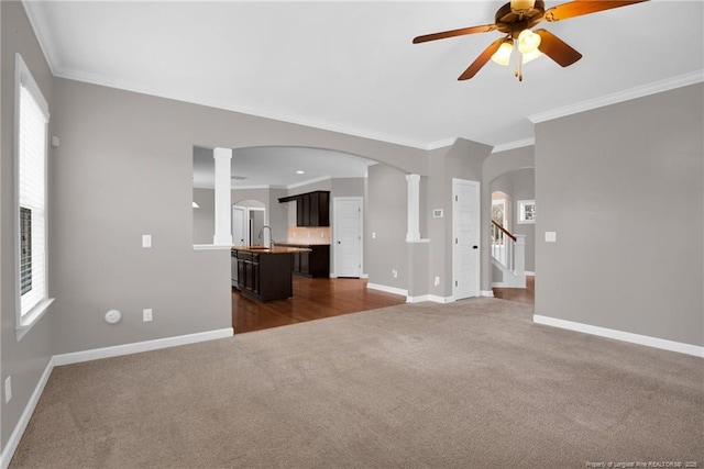 unfurnished living room with crown molding, ceiling fan, sink, and dark colored carpet