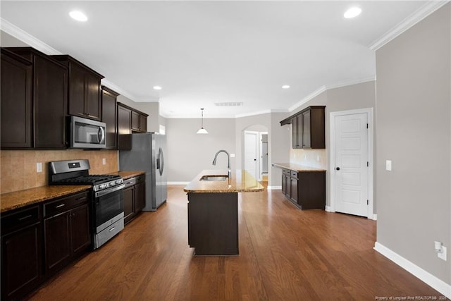 kitchen featuring dark hardwood / wood-style floors, pendant lighting, sink, stainless steel appliances, and a center island with sink