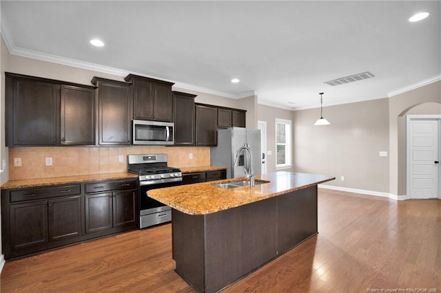 kitchen with sink, light hardwood / wood-style flooring, hanging light fixtures, stainless steel appliances, and an island with sink