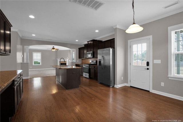 kitchen with sink, crown molding, stainless steel appliances, an island with sink, and decorative light fixtures