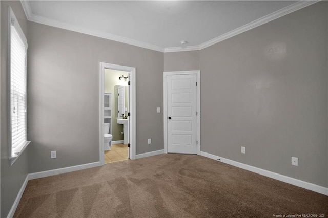 unfurnished bedroom featuring ensuite bath, ornamental molding, and light carpet