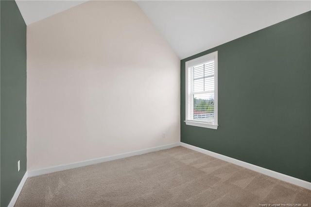 carpeted spare room featuring vaulted ceiling