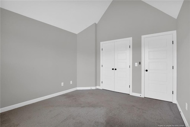 spare room featuring high vaulted ceiling and dark carpet