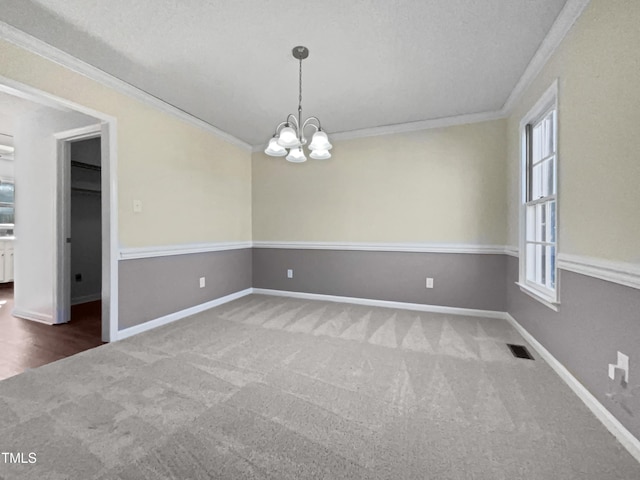 unfurnished room featuring an inviting chandelier, crown molding, plenty of natural light, and carpet