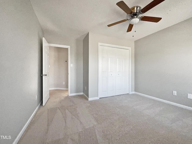 unfurnished bedroom featuring light carpet, a textured ceiling, ceiling fan, and a closet